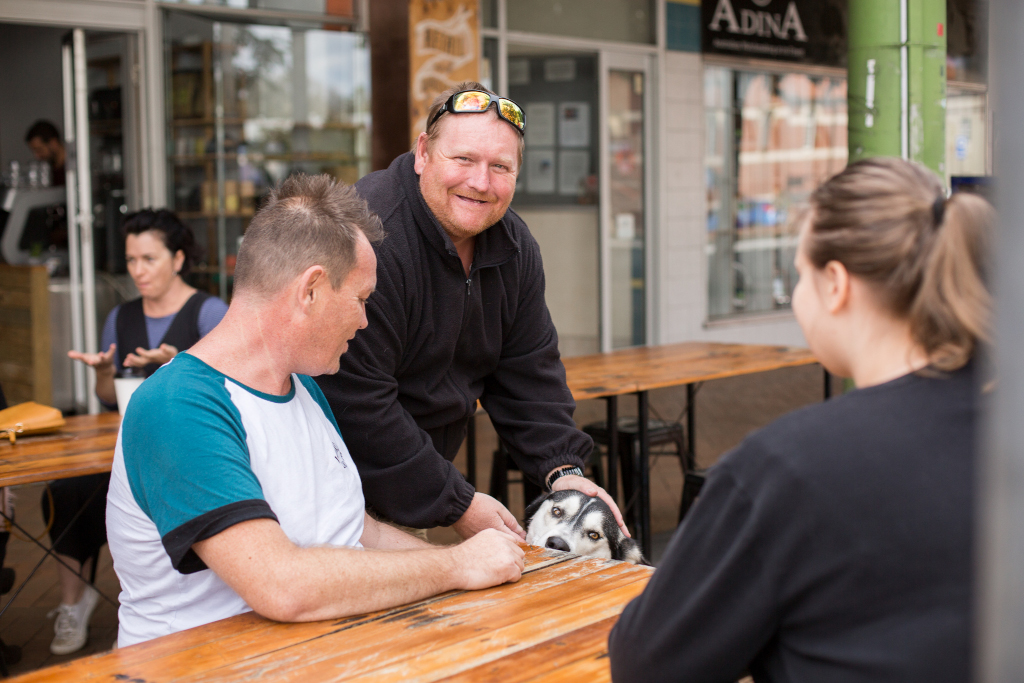 A client patting a husky at an outside cafe